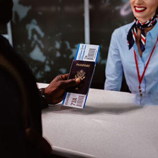 Close-up of man's hand holding passport and boarding pass at airline check-in desk at airport